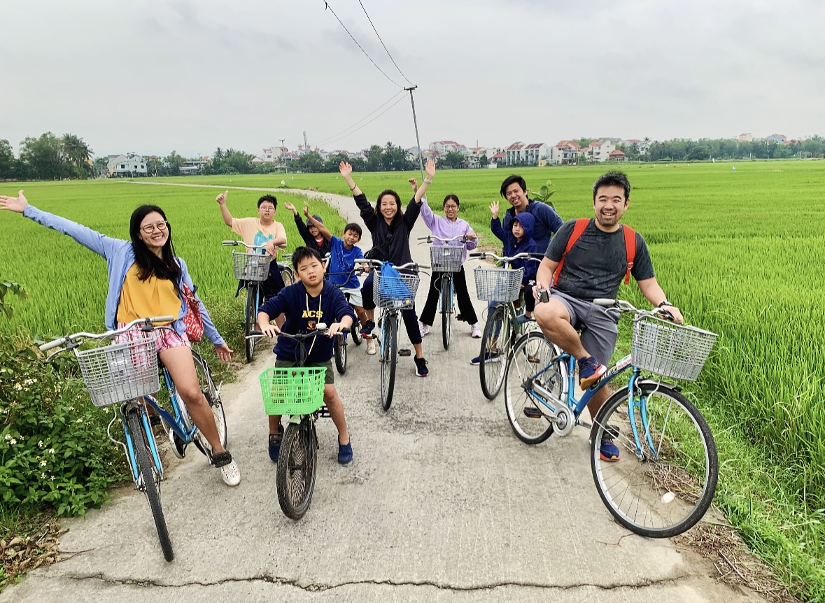 Person cycling through fields in Tra Que Village, scenic bike tour Hoi An countryside