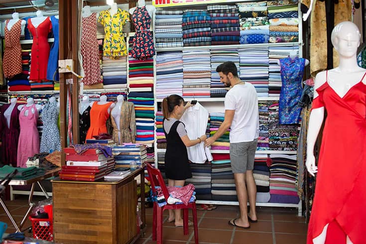 Rows of colorful fabrics in a Hoi An tailor shop, highlighting the custom clothing experience, a popular Hoi An activity.
