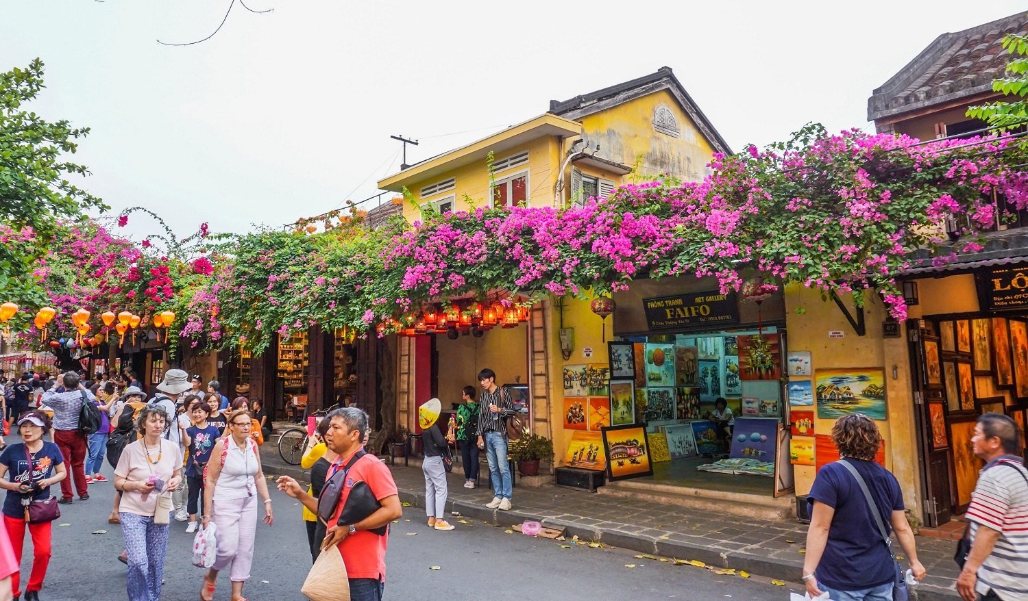 Tourists walking through Hoi An Ancient Town during the day, exploring historic streets and architecture, a top thing to do in Hoi An.