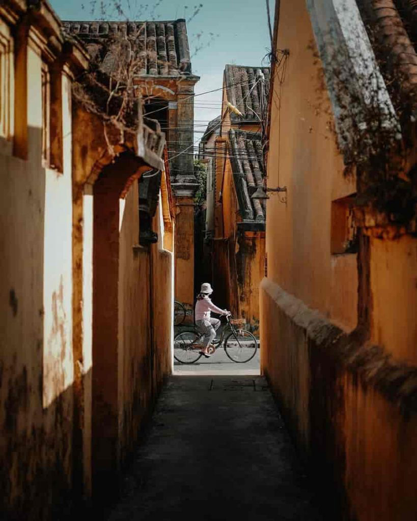 Hidden gems Hoi An: Serene, narrow alleyway in Hoi An Ancient Town with potted plants and traditional architecture.