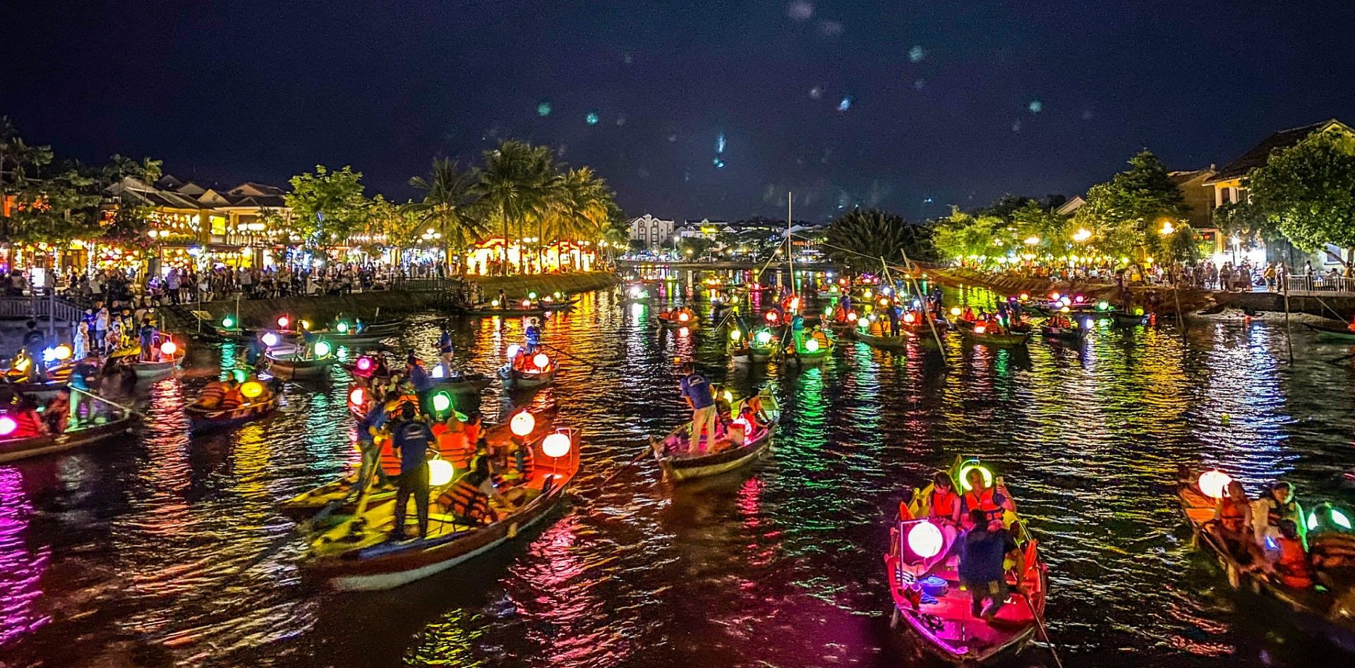 Lantern-lit boats on the Thu Bon River in Hoi An at night, a romantic and popular Hoi An activity.