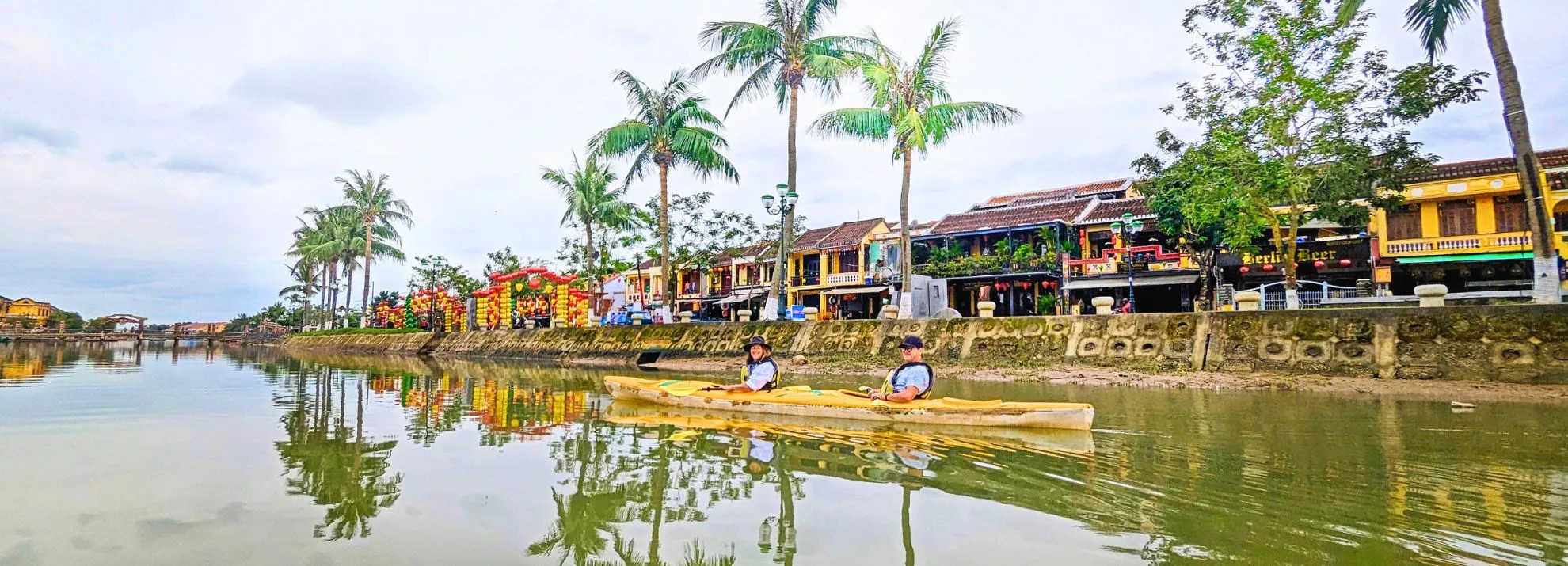 People cycling through green rice paddies with water buffalo in Hoi An countryside, a serene thing to do in Hoi An.